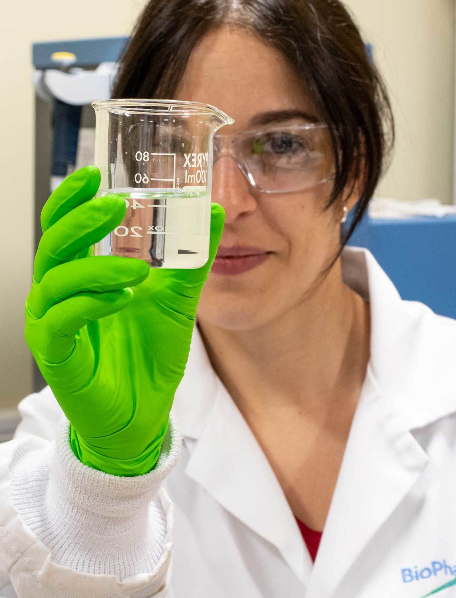 scientist looking into beaker of liquid